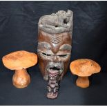 A large carved hardwood African mask, together with two carved wooden mushrooms and a small wooden t