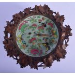 A 19TH CENTURY CHINESE CANTON FAMILLE ROSE PORCELAIN DISH within a black forest frame. 24 cm x 10 cm