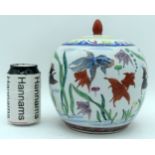 A Chinese porcelain polychrome lidded ginger jar decorated with fish. 21cm (2)