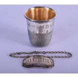 A RARE OVERSIZED VINTAGE THIMBLE together with a silver decanter label. 52 grams. Largest 5 cm x 4.5