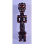 AN AFRICAN TRIBAL CARVED WOOD MUSCULAR FIGURE modelled with hands clasped. 23 cm high.
