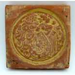 An early terracotta tile decorated with a soldier carrying a shield and a coat of arms 10cm .
