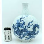 A Chinese porcelain blue and white moon flask decorated with a dragon and clouds in relief. 32cm