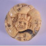 A JAPANESE BONE NETSUKE CARVED WITH FACES. 4cm diameter, 1.5cm wide, weight 27g
