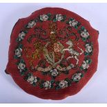 AN ANTIQUE BEADWORK ARMORIAL CUSHION. 25 cm diameter.