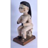 AN AFRICAN WHITE PAINTED TRIBAL CARVED WOOD FIGURE modelled upon a stool. 40 cm high.