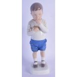 A ROYAL COPENHAGEN PORCELAIN FIGURE OF A BOY modelled eating fruit. 18 cm high.