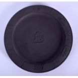 A WEDGWOOD BLACK BASALT CIRCULAR PLATE decorated with cupid figural group, the rim with similar deco