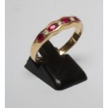 A RUBY HALF HOOP RING, the five oval facet cut stones horizontally channel set with four small round