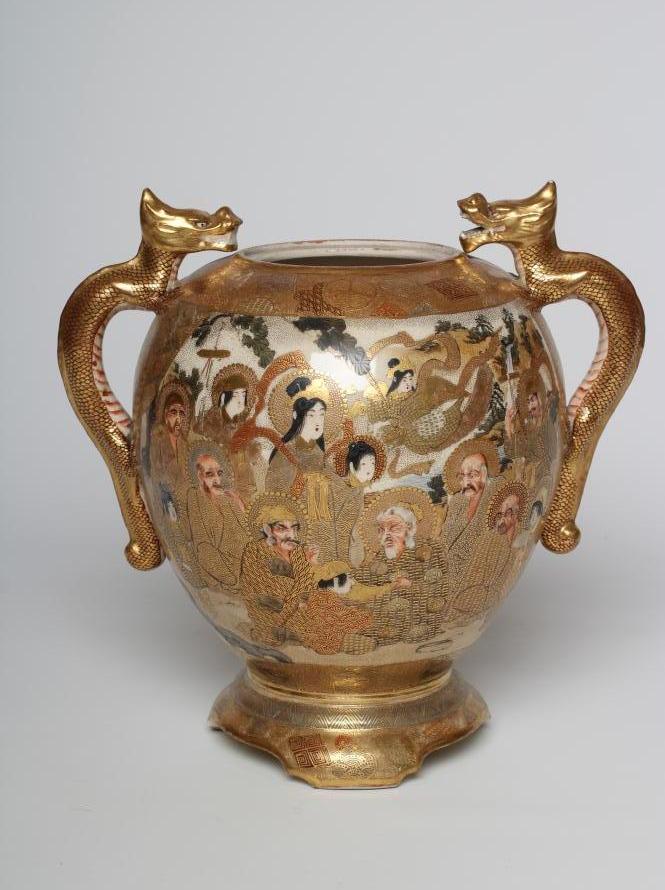 A SATSUMA EARTHENWARE VASE of rounded flared form with two dragon handles and raised upon a fixed "