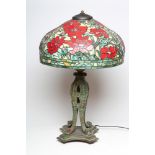 A LARGE TIFFANY STYLE TABLE LAMP, modern, the leaded red floral shade on a verdigris bronzed metal