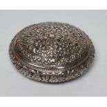 A WHITE METAL BOX, unmarked, possibly Burmese, of oval cushion form, all over chased with
