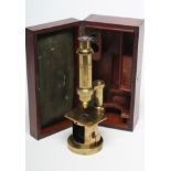 A LACQUERED BRASS STUDENT FIELD MICROSCOPE, early 20th century, in mahogany box with lenses and