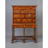 A WALNUT CHEST ON STAND, early 18th century and later, the quarter veneered and feather banded top