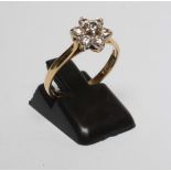 A DIAMOND CLUSTER RING, the seven round brilliant cut stones claw set in a flowerhead to a plain