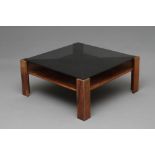 A ROSEWOOD VENEERED COFFEE TABLE, 1970s, of square X form with smoke glass top, raised on four