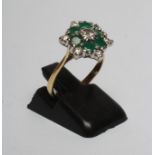 A DIAMOND AND EMERALD CLUSTER RING, the central diamond of approximately 0.20cts claw set to a