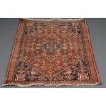A PERSIAN TRIBAL RUG, modern, the large red field with trailing flowers and leaves and centred by