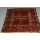 AN AFGHAN RUG, the quartered burgundy field of candelabra design, with a geometric surround with