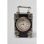 A LATE VICTORIAN SILVER MOUNTED TORTOISESHELL DRESSING TABLE TIMEPIECE, the circular white enamel