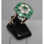 AN EMERALD AND DIAMOND CLUSTER RING, the flower panel point set with six brilliant cut diamonds