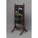 A REGENCY MAHOGANY CHEVAL MIRROR, the oblong plate suspended on moulded square uprights with