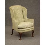 A WALNUT FRAMED WING ARMCHAIR, 19th century, of early Georgian design upholstered in a pale green