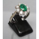 AN EMERALD AND DIAMOND CLUSTER RING, the cushion cut emerald claw set to a border of eight round