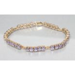 A TANZANITE BRACELET, the seven panels each claw set with five cushion cut stones to a 9ct gold
