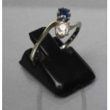 A SAPPHIRE AND DIAMOND CROSSOVER RING, the cushion cut stones claw set to a plain white shank,
