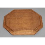 A ROBERT THOMPSON OAK CHOPPING BOARD of canted oblong form, the moulded edge with carved mouse
