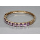 A STIFF HINGED BANGLE, the upper section set with nine square cut amethysts with diamond point