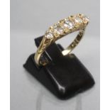 A FIVE STONE DIAMOND RING, the graduated brilliant cut stones set to carved shoulders and a plain
