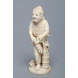 A JAPANESE IVORY OKIMONO, Meiji period, carved as a smiling man holding a pair of shears in his left