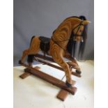 A Wolf House Gallery rocking horse, with carved laminated wood body, open mouth, leather saddle,