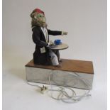 An electrically driven monkey automaton in dressing gown and pyjamas seated at a table, plate,