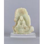 A CHINESE JADE DEITY seated before rockwork with engraved and stained red and gilt script, the