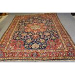 A PERSIAN RUG, the navy blue floral field with similar red and ivory gul, conforming spandrels,