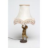 A GILT METAL TABLE LAMP, 20th century, modelled as a dancing cherub, on rustic bronzed base with