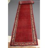 A PERSIAN STYLE WOOL RUNNER, late 20th century, the red field with repeating flower motif in blue