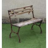 A SMALL VICTORIAN CAST IRON BENCH, the slatted wood back and seat on scroll and foliate cast X end