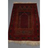 AN AFGHAN PRAYER RUG, the mihrab with red and navy blue geometric pattern in blue spandrels with