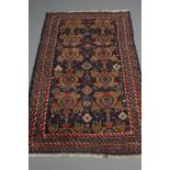 A PERSIAN TRIBAL RUG, the navy blue field with two rows of repeating guls in shades of cream, brown,