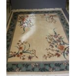 A CHINESE WASHED AND FRINGED CARPET, the plain champagne field with large floral sprays to each