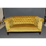 AN EDWARDIAN MAHOGANY FRAMED CHESTERFIELD SOFA with drop ends, button upholstered in yellow