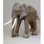 A REPLICA LEATHER COVERED MODEL OF AN ELEPHANT, with glass eyes, with composition tusks, 48" high,