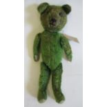 A pre-war green jointed teddy, with shoe button eyes, sewn nose and felt pads, 13 1/4" long (Est.