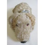 A Merrythought lying dog, with sewn nose, amber eyes, cloth pads, light orange plush, label to