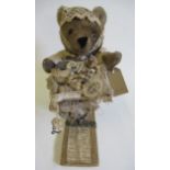 A shop display teddy, modelled selling haberdashery items, standing at a table, with grey plush,
