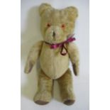 A vintage teddy bear, with sewn nose, amber plastic eyes, felt pads and swivel joints, 21 1/4" long,